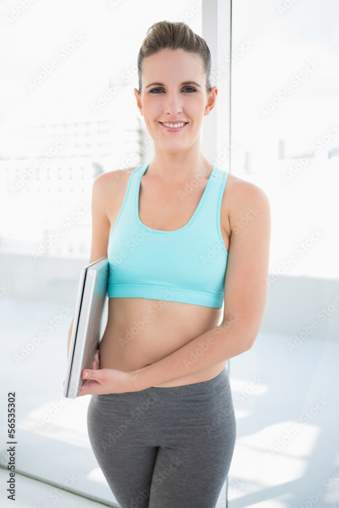 Cheerful woman in sportswear holding laptop