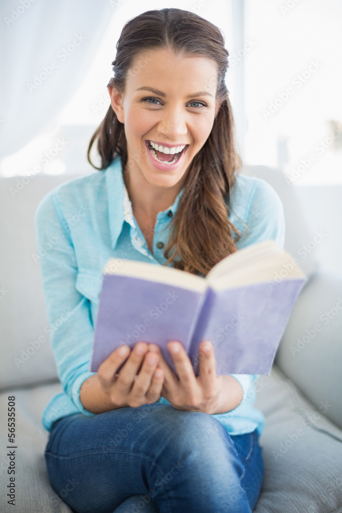 Smiling woman sitting on couch holding book Smiling woman sitting on couch holding book