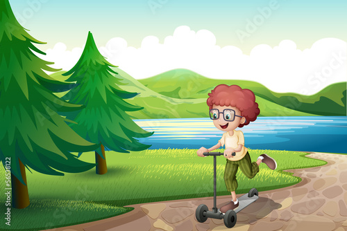 A boy playing with his scooter near the river