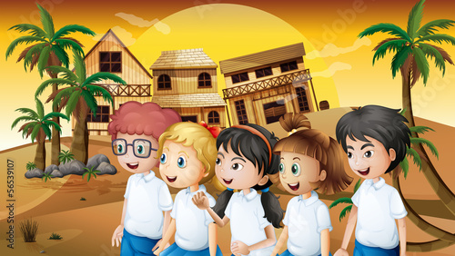 A group of students strolling at the desert with wooden barnhous