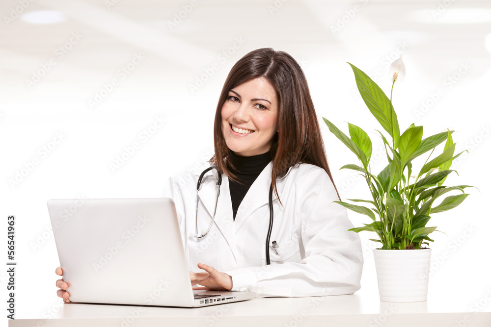 Female doctor sitting at her desk and smiles towards the camera Female doctor sitting at her desk and smiles towards the camera