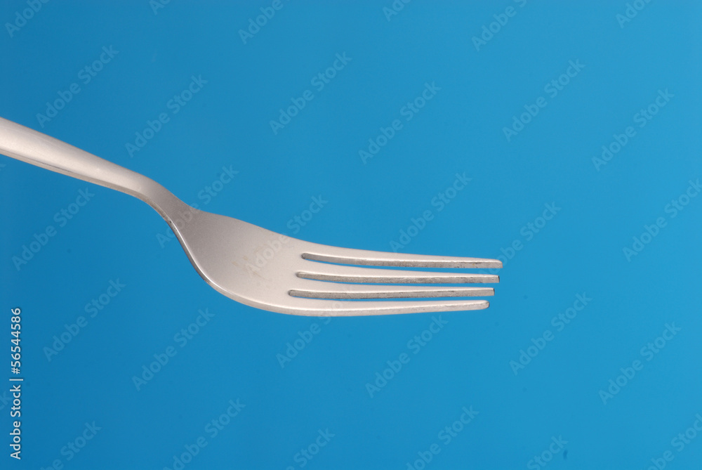 Detalle de un tenedor sobre fondo azul.