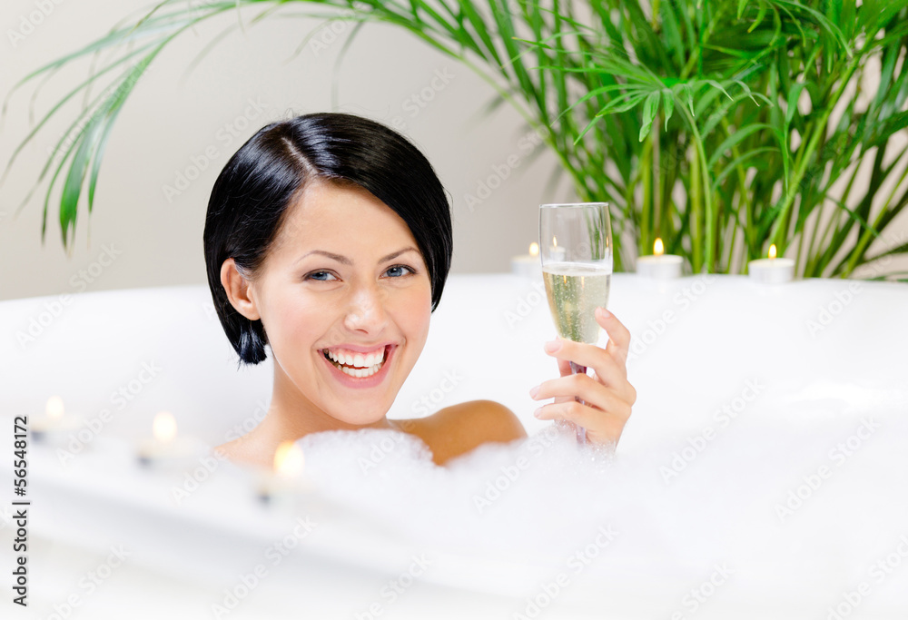Woman taking a bath with suds drinks alcohol and relaxes Woman taking a bath with suds drinks alcohol and relaxes