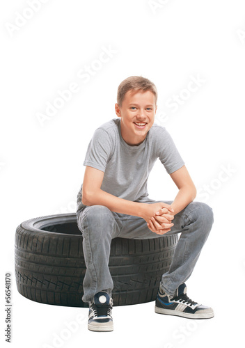 Smiling teenager sitting on a car tire