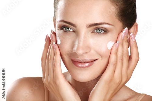 beautiful model applying cosmetic cream treatmen on her face photo