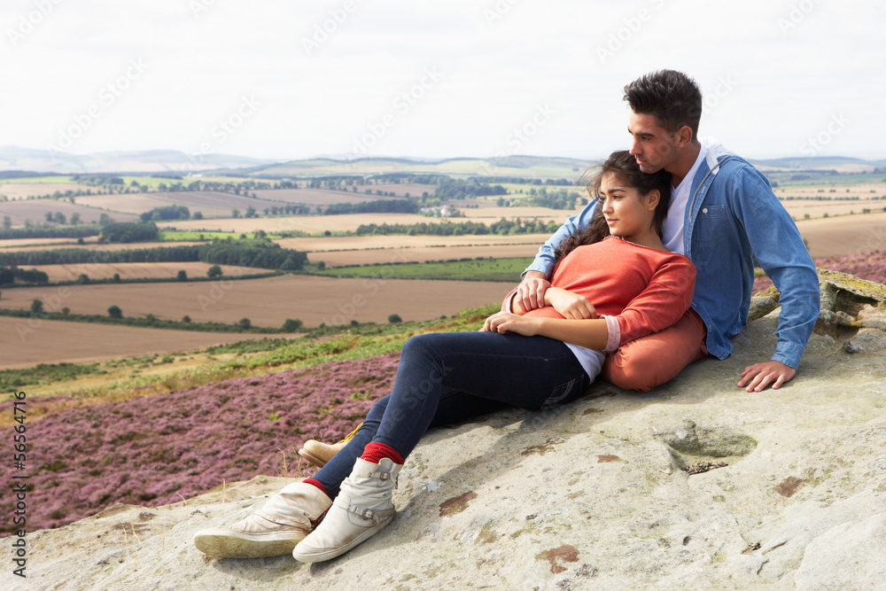 Young Couple Sitting On Rock Admiring View