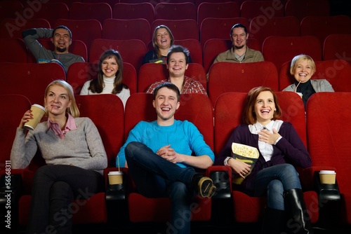 Group of smiling people watching movie in cinema