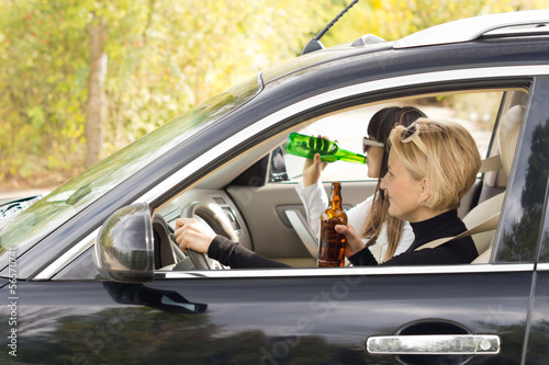 Two women driving a car while drinking photo