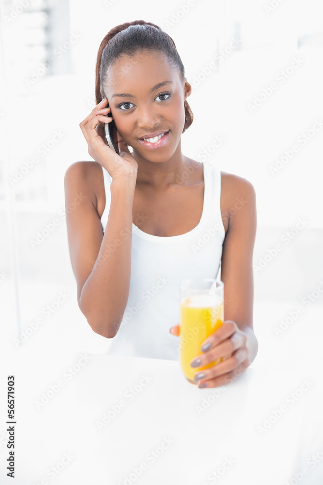 Happy athletic woman phoning holding orange juice Happy athletic woman phoning holding orange juice