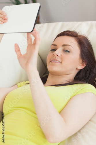 Happy teen girl lying on a sofa using a tablet pc