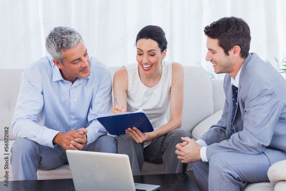 Woman signing contract as husband and salesman watch Woman signing contract as husband and salesman watch