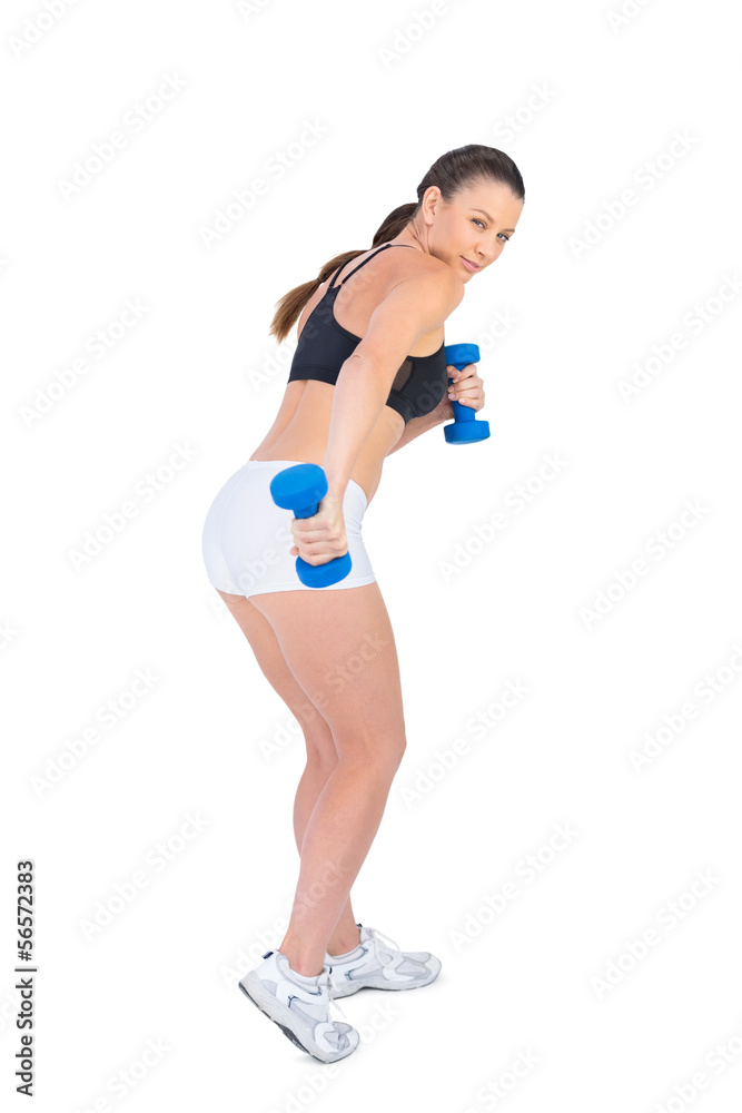 Concentrated sporty brunette exercising with dumbbells