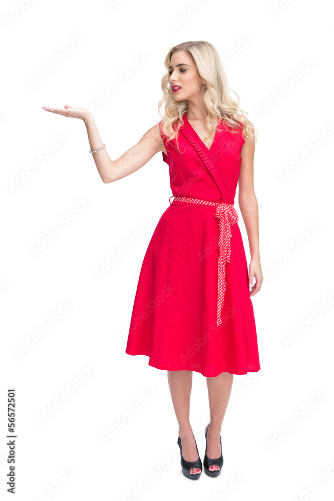 Smiling woman in red dress presenting something in her hand Smiling woman in red dress presenting something in her hand