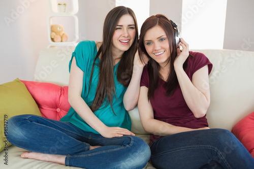 Smiling girl listening to music with her friend beside her on th © WavebreakMediaMicro