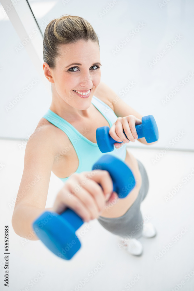 Fit smiling woman exercising with dumbbells Fit smiling woman exercising with dumbbells