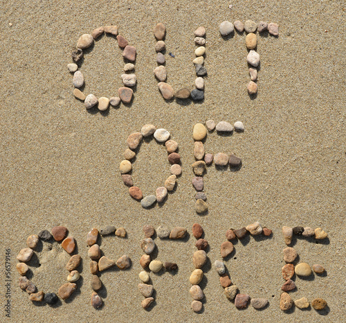 Out of office text written on the beach sand
