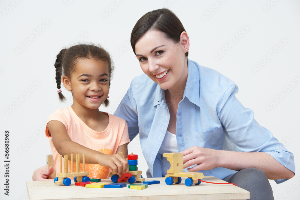 Teacher And Pre-School Pupil Playing With Wooden House Teacher And Pre-School Pupil Playing With Wooden House