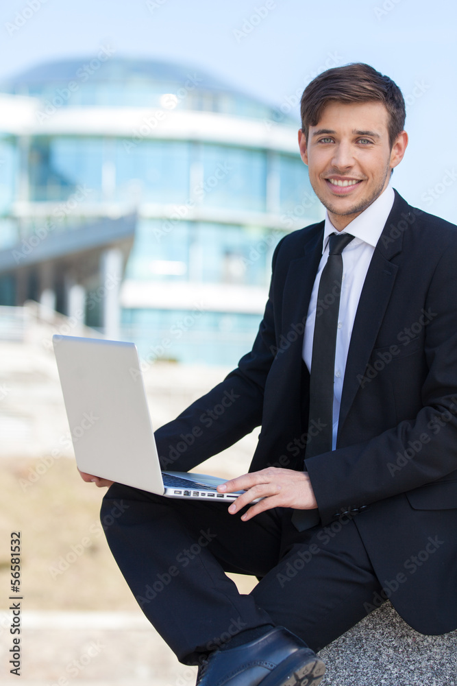 Successful businessman. Cheerful young men in formalwear using l Successful businessman. Cheerful young men in formalwear using l