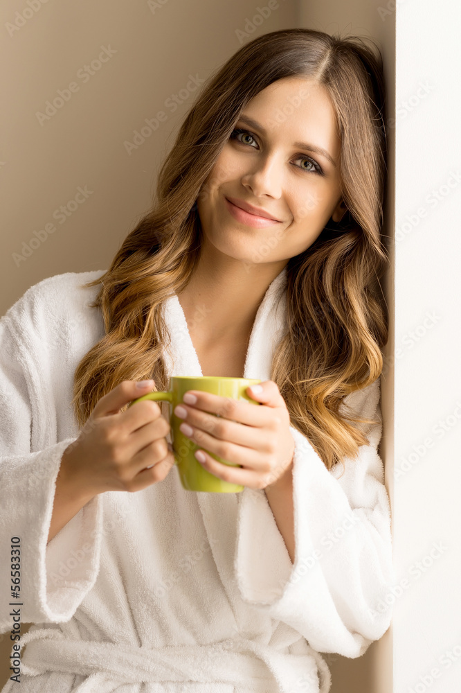 Drinking coffee at home. Beautiful young woman in bathrobe drink Drinking coffee at home. Beautiful young woman in bathrobe drink
