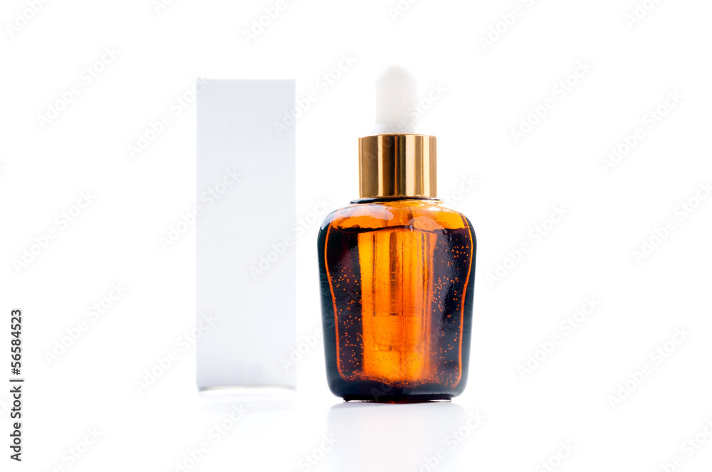 Pipette with drop of cosmetic oil above brown bottle with box