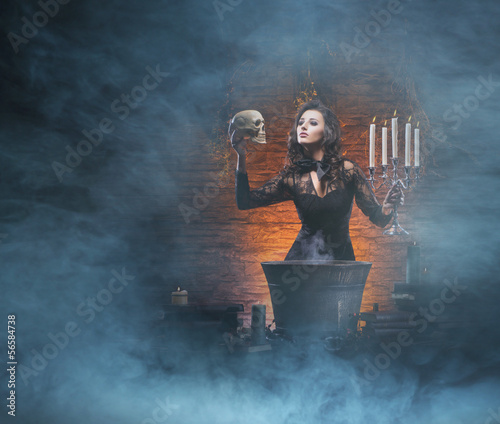 A young and sexy witch making a deadly poison with a skull