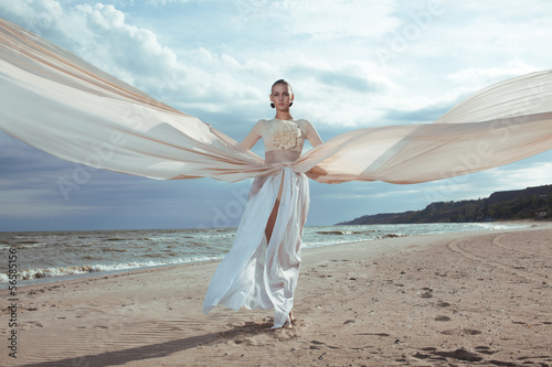 model in long beige dress posing dynamic in  waving fabric