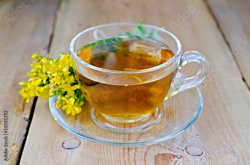 Herbal tea from tutsan in a glass cup on a board