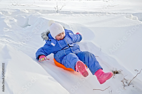 Canvastavla Little girl on a sled sliding on snow