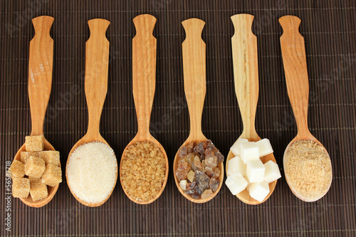 Different types of sugar in spoons on table close-up
