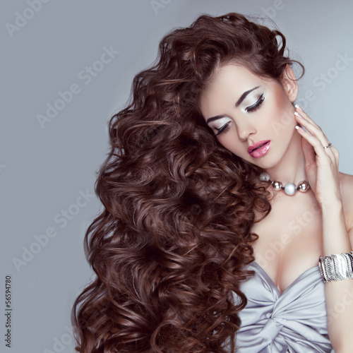 Portrait of a beautiful brunette woman with long wavy hair poses