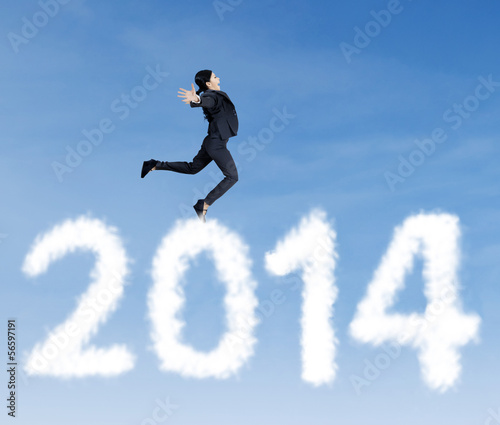 Businesswoman jumping over clouds of 2014