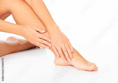 Woman touches her leg, white background, copyspace.