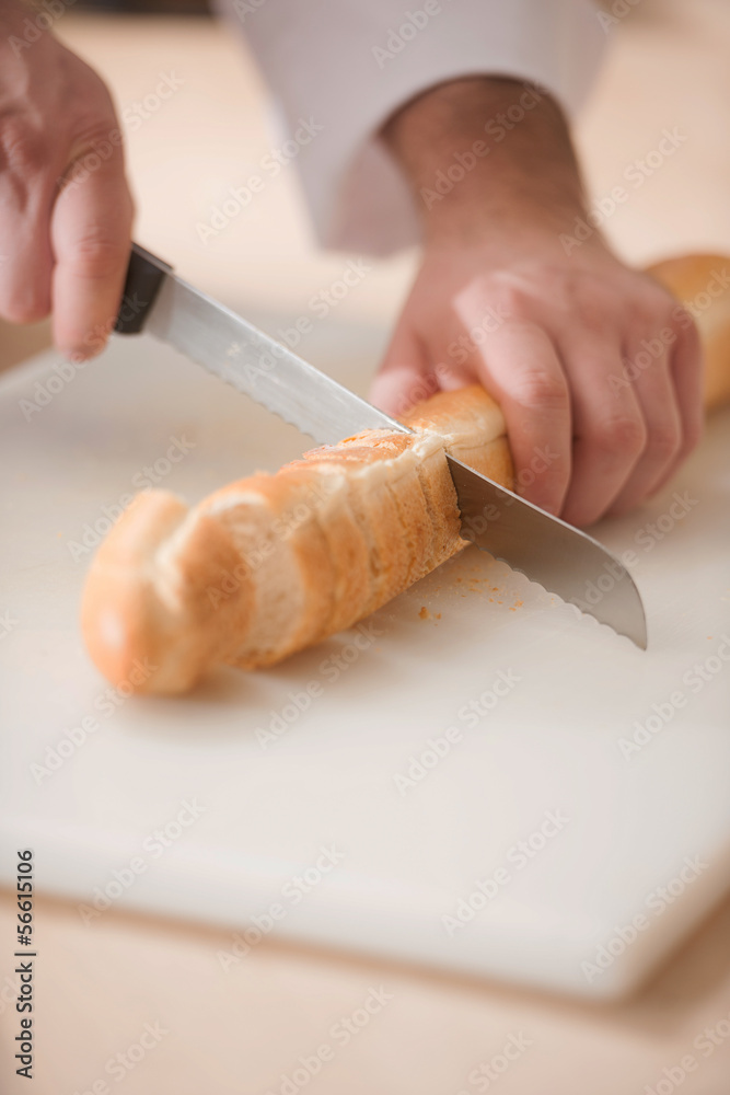 Cutting bread. Close-up top view of chef cutting fresh bread