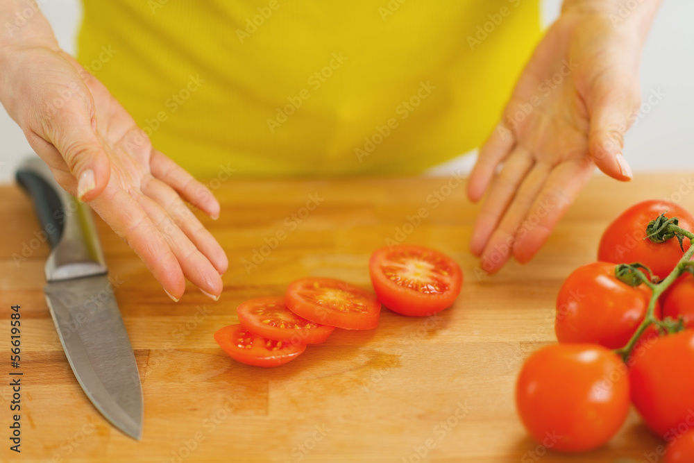 Closeup on woman showing slices of tomato on cutting board