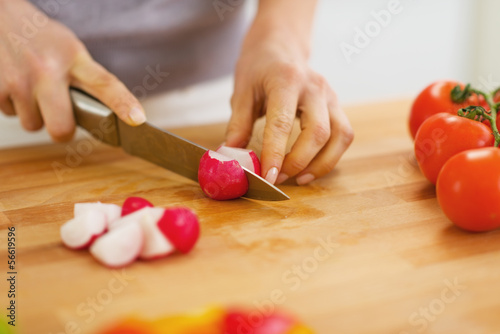 Closeup on woman cutting radishes on cutting board