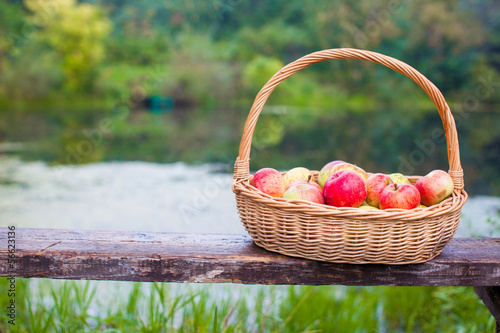 Close up of Big straw basket with red and yellow apples on a