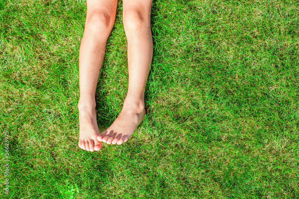 Close-up of two legs of a young girl on the grass on the lawn