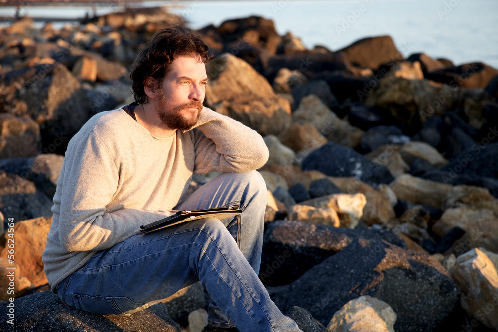 Man relaxing on beach while working with tablet during sunset Man relaxing on beach while working with tablet during sunset