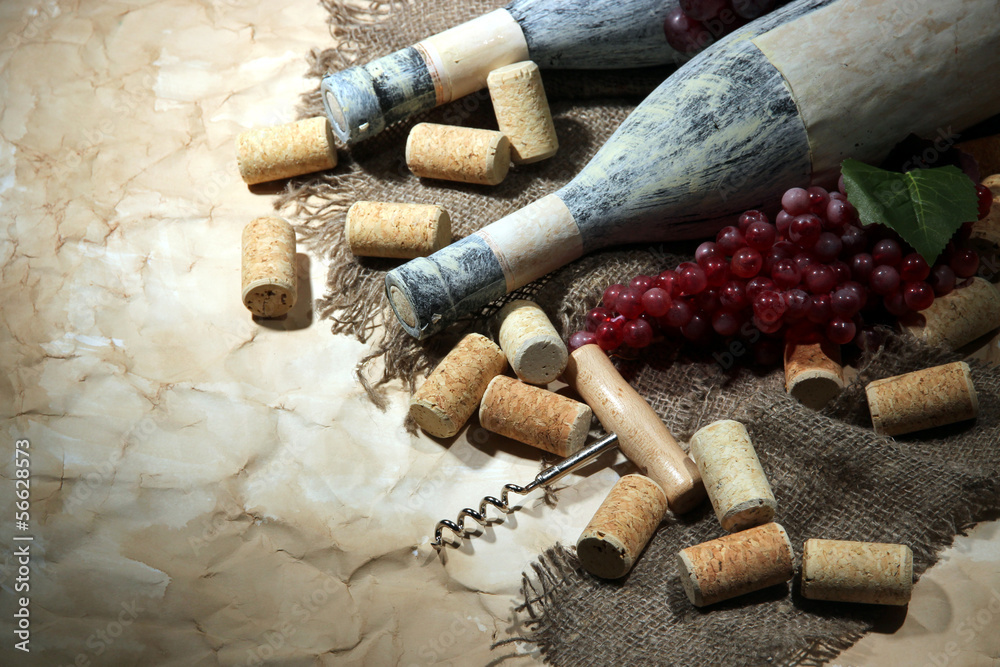 Old bottles of wine, grapes and corks on old paper background