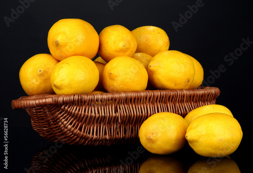 Ripe lemons in wicker basket isolated on black