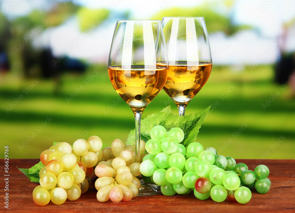 Ripe grapes and glasses of wine, on bright background