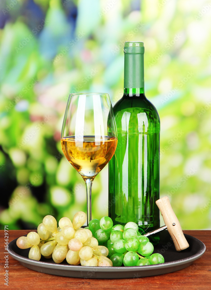 Fototapeta premium Wine bottle and glass of wine on tray, on bright background