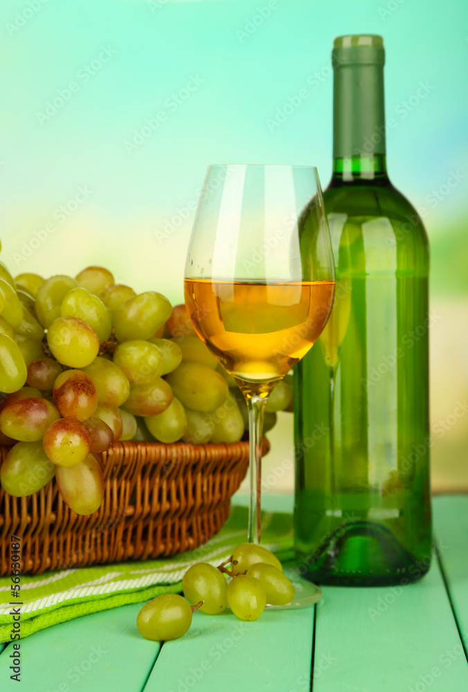 Ripe grapes in wicker basket, bottle and glass of wine,
