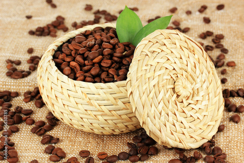 Coffee beans in wicker basket on table close-up