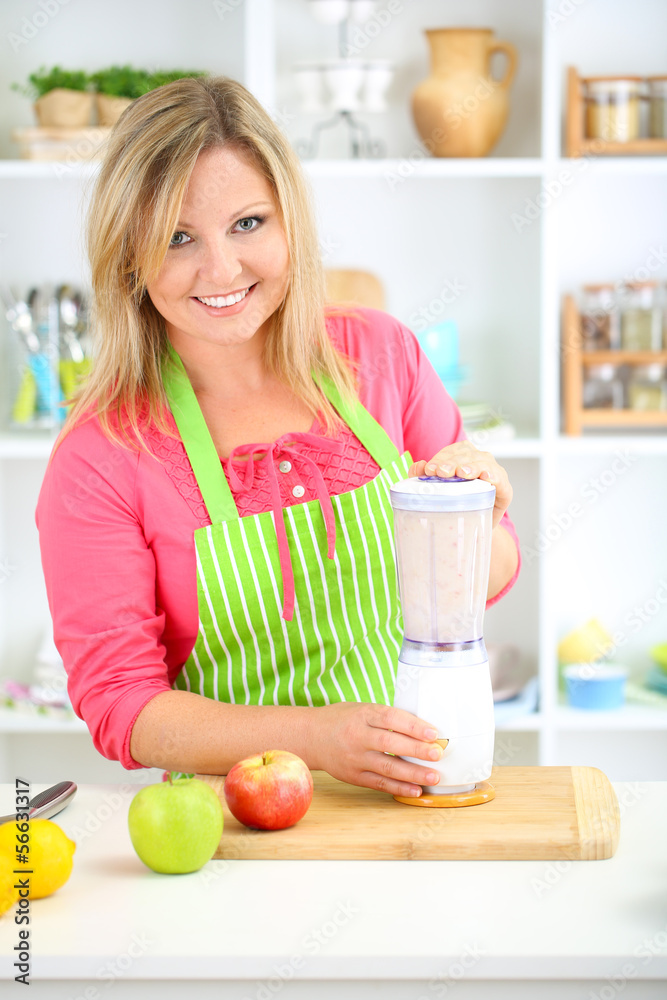 Happy smiling woman in kitchen preparing fresh fruit cocktail Happy smiling woman in kitchen preparing fresh fruit cocktail