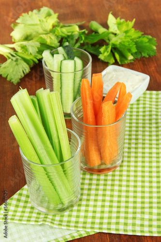 Fresh green celery with vegetables in glasses on table close-up