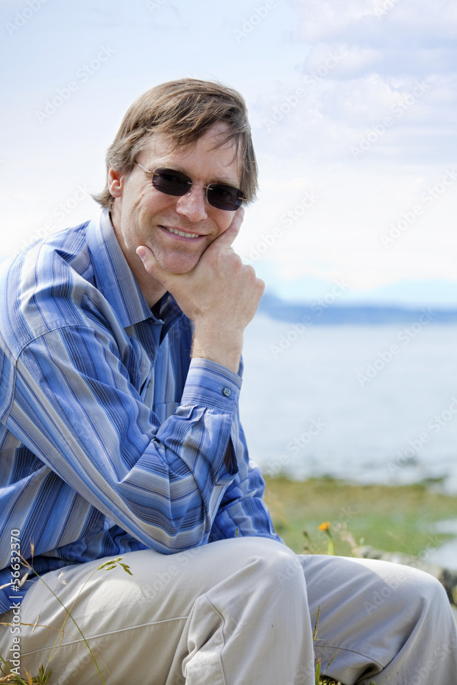 Handsome Causcasian man in forties relaxing by lake side