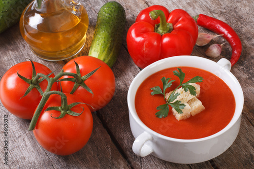 Tomato gazpacho and fresh vegetables on a wooden table. top view