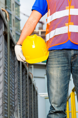 Worker on construction site with helmet or hard hat photo