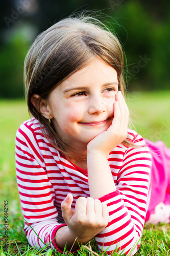 a beautiful young girl lays in a field photo